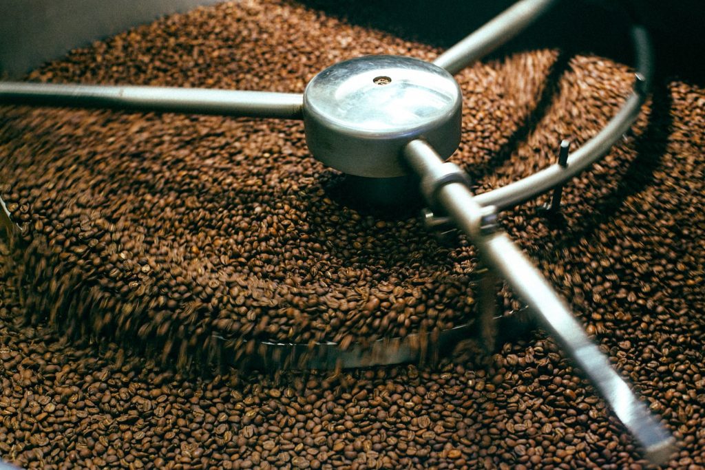 From above of fresh aromatic brown coffee beans mixing in professional roasting machine